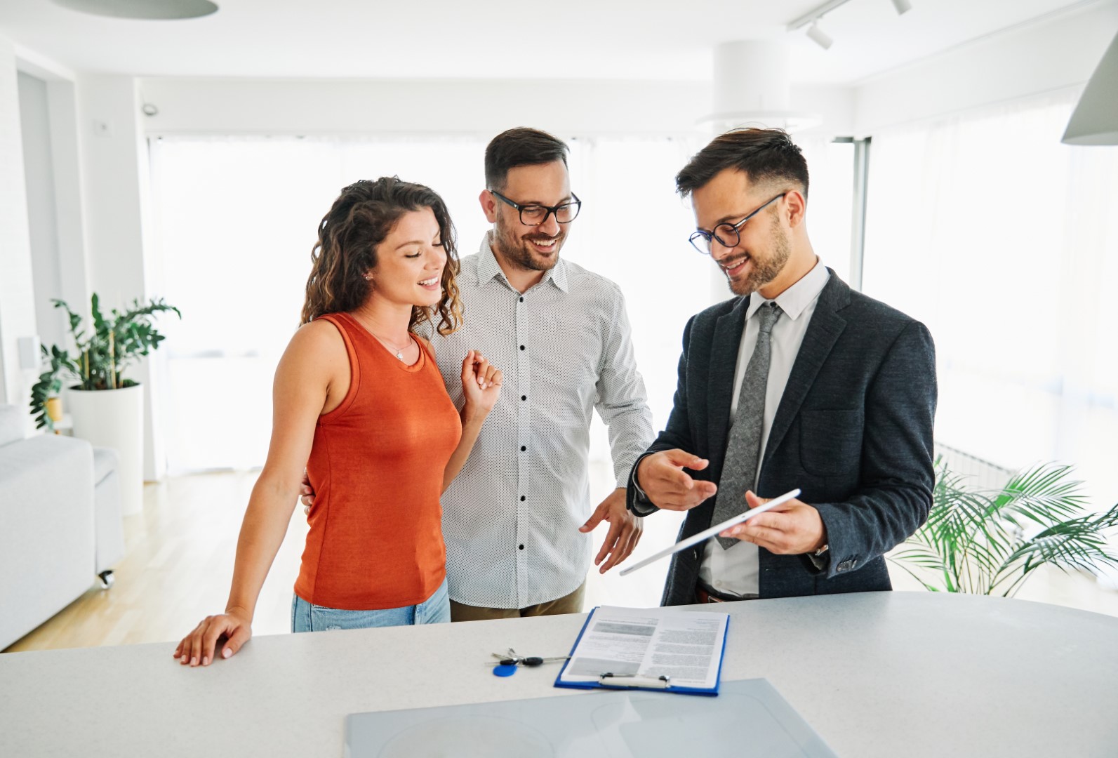 Real estate agent showing young couple 149Photos on tablet